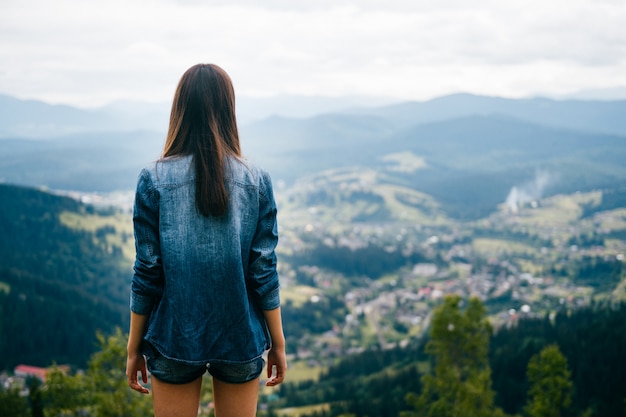 Teen brunette girl posant au sommet de la montagne en été.