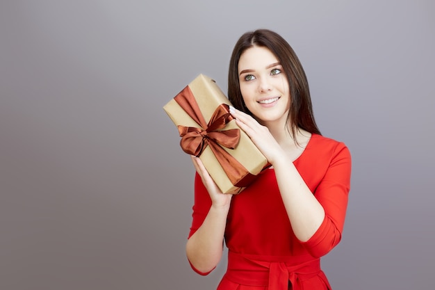 Teen femme brune dans une robe rouge vif reçoit un cadeau pour les vacances.