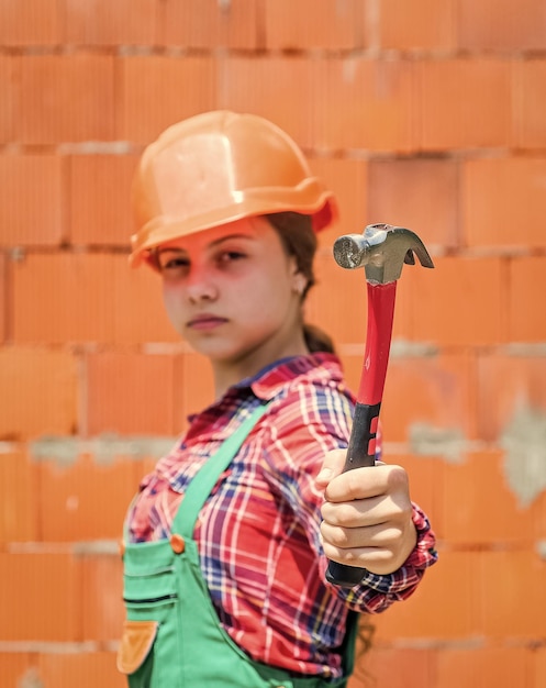 Teen girl builder dans un casque de protection utiliser un outil de construction de marteau