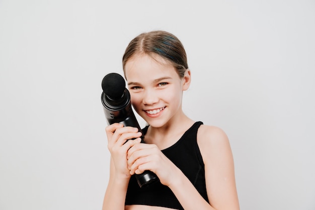 Teen girl détient un pistolet de massage.