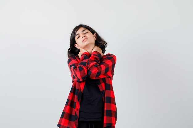 Teen girl holding hands on cou en t-shirt, chemise à carreaux et à la douleur. vue de face.