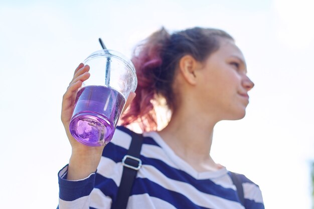 Teen girl holding verre avec de la paille avec un verre violet à la main