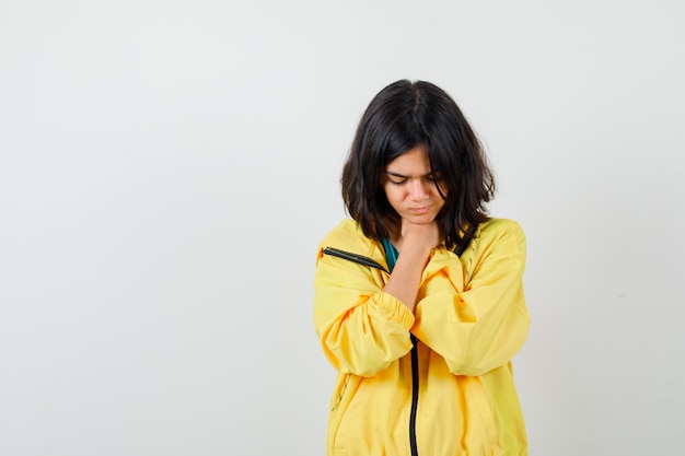 Teen girl in yellow jacket souffrant de maux de gorge et à la colère , vue de face.