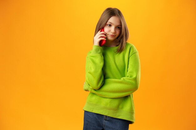 Photo teen girl sur mur jaune parlant sur smartphone