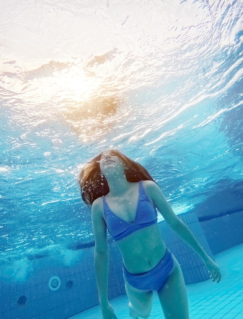 Teen girl nager sous l'eau dans la piscine bleue jolie adolescente plonger et profiter des activités d'été