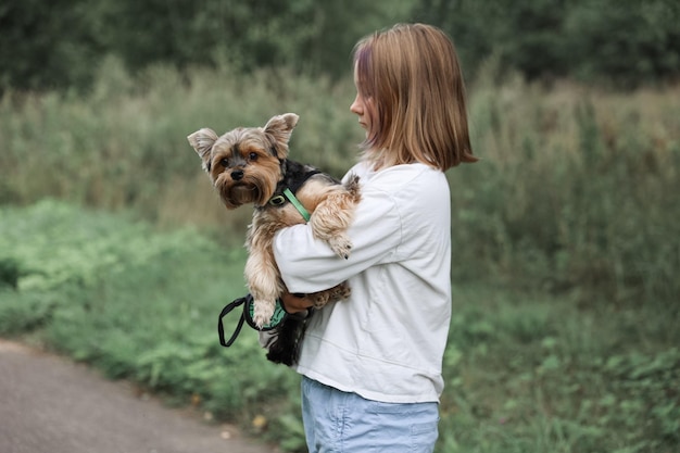 Teen girl sur une promenade dans le parc d'été avec son animal de compagnie Yorkshire terrier. Enfant promenant un chien