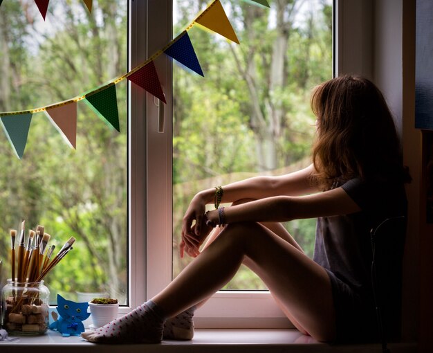 Teen girl sitting on a window in the children's room