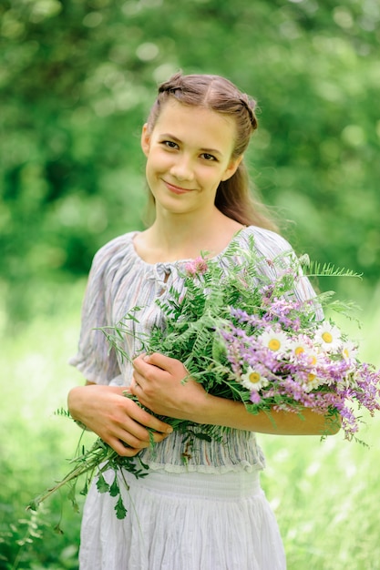 Teen girl tient un bouquet de fleurs dans ses mains.