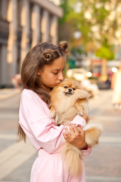 Teen girl with pet animal petit chien tenant dans une main en plein air dans un parc.