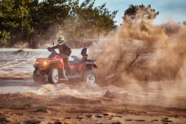 Teen riding ATV dans les dunes de sable faisant un tour dans le sable