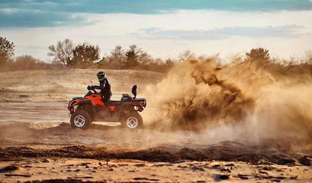 Teen riding ATV dans les dunes de sable faisant un tour dans le sable