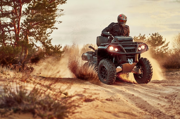 Teen riding ATV dans les dunes de sable faisant un tour dans le sable