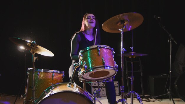 Teen rock music - le batteur de percussions de jolie fille exécute la musique en panne, horizontale