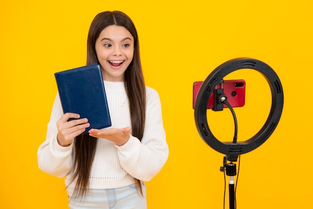 Teen school girl parlant devant la caméra pour vlog isolé sur fond jaune Adolescent travaillant comme blogueur enregistrant un blog vidéo