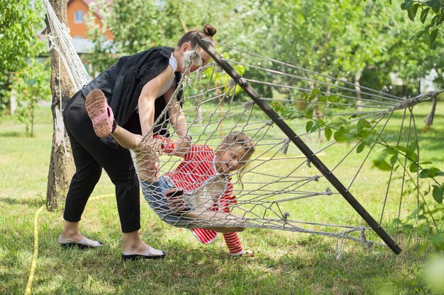 Teen soeur filles et enfant s'amusant sur un hamac dans le jardin de l'arrière-cour, happy laughing girls