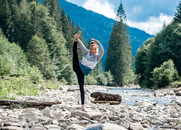 Teenage girl dancing debout sur la pierre à la rivière de montagne