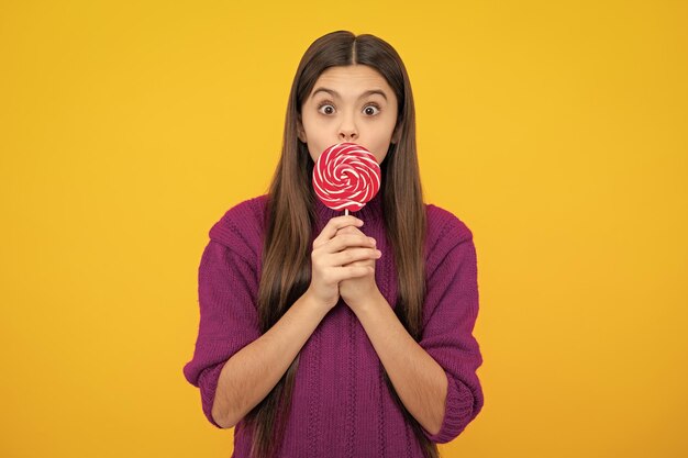 Teenage girl with candy lollipop happy child 12 13 14 ans eating big sugar lollipop sweets candy Émotions surprises d'une jeune adolescente