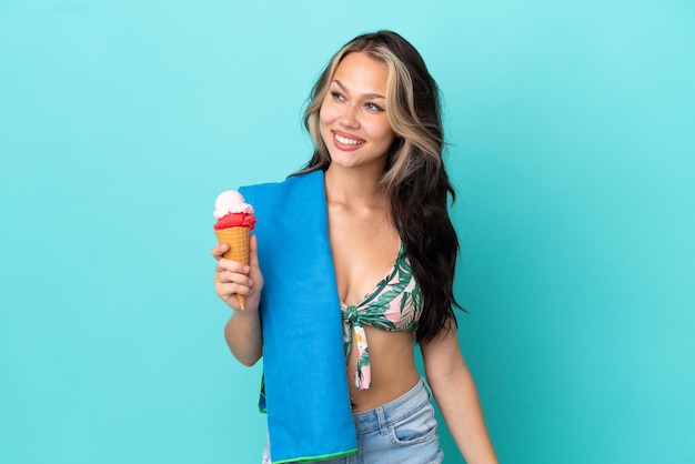 Teenager caucasian girl holding ice cream et serviette isolé sur fond bleu à côté