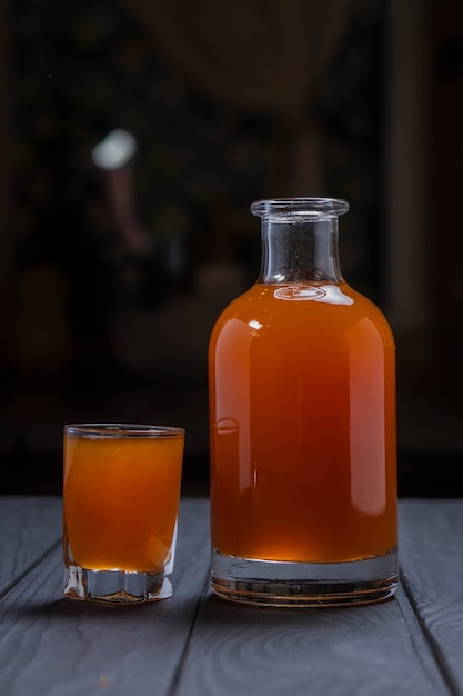 Teinture de canneberge rouge maison ou liqueur sur une surface en bois noir