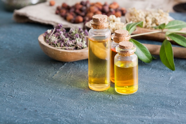 Teintures d'herbes dans des bouteilles en verre sur une table en béton foncé. Médecine traditionnelle et concept de traitement à base de plantes.