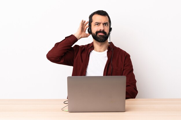 Telemarketer homme caucasien travaillant avec un casque et avec un ordinateur portable ayant des doutes