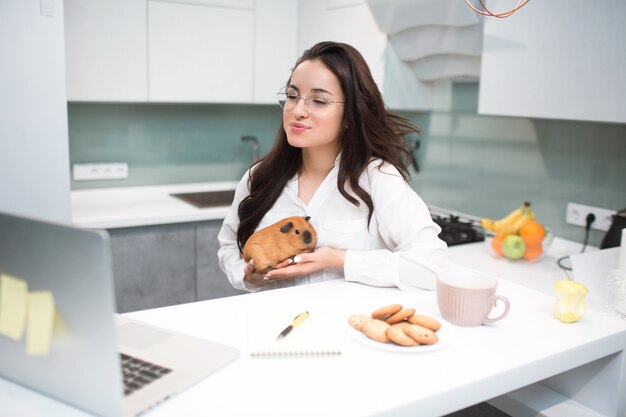 Télémédecine, consultation vétérinaire en ligne. Une jeune femme tient un cochon d'Inde. Un médecin conseille le patient