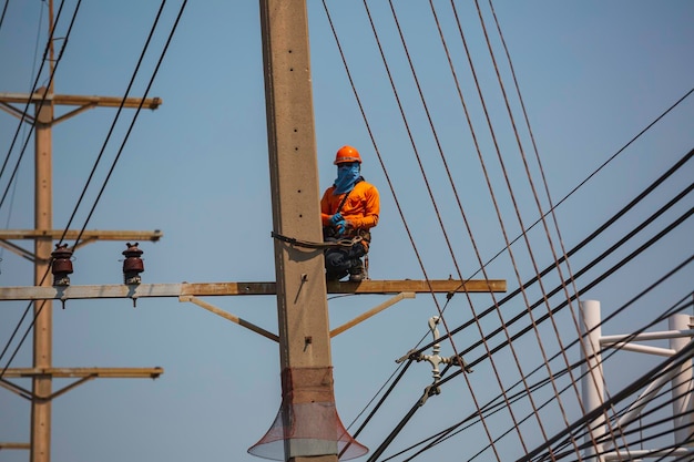 Le téléphérique de la grue du travailleur masculin répare le poteau électrique et se développe autour des lignes électriques