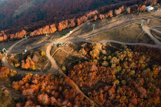 Téléphérique menant à la crête de la montagne et aux pistes de ski s'étendant le long des pentes des collines sous des nuages blancs flottant sur le ciel bleu le jour de l'automne