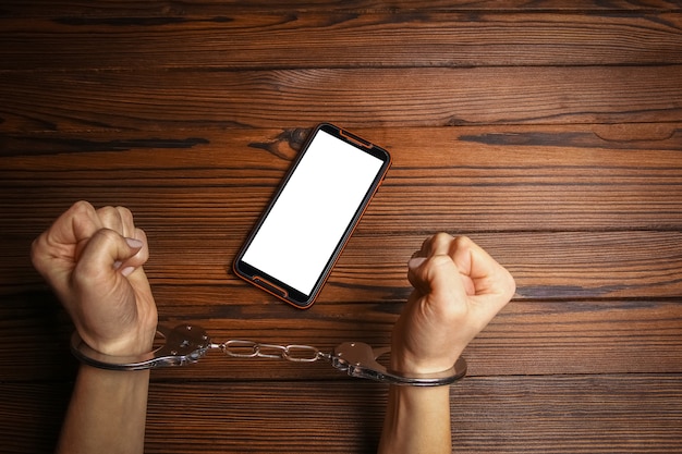 Téléphone avec addiction mains sur une surface en bois