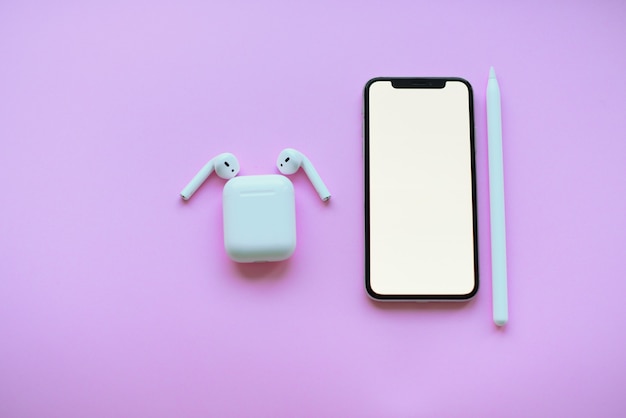 téléphone et air pods et crayon sur fond rose