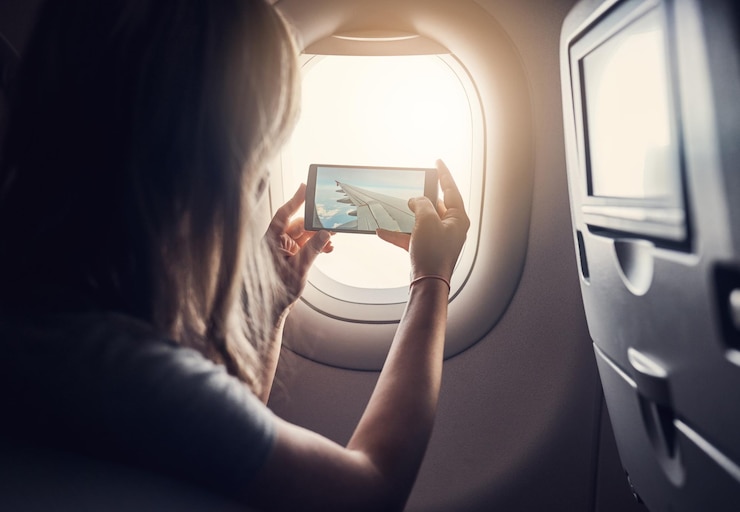 Photo téléphone d'avion et femme par la fenêtre pour une photo sur les voyages internationaux et les trajets mondiaux photographie de transport et passager dans l'avion avec vue sur l'aventure de vacances et le souvenir des vacances