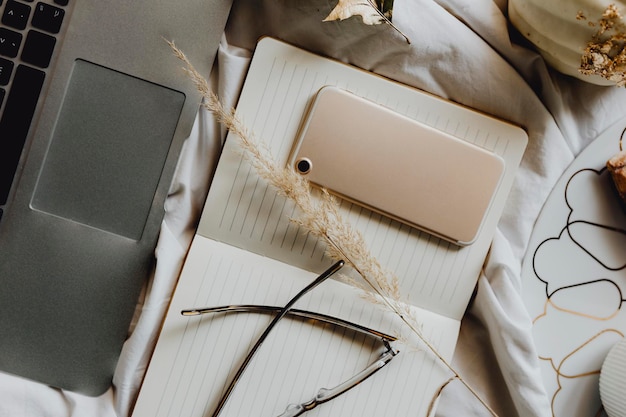 Téléphone sur un bloc-notes à côté d'un ordinateur portable sur un lit