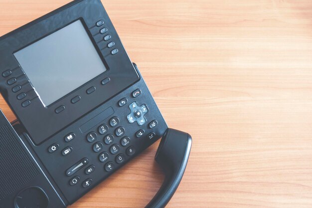 Photo le téléphone à bouton-poussoir de bureau noir téléphone ip sur le bureau dans le concept de communication de bureau libre