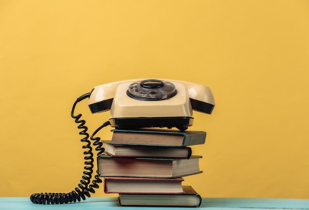 Téléphone à cadran sur une pile de livres. Jaune