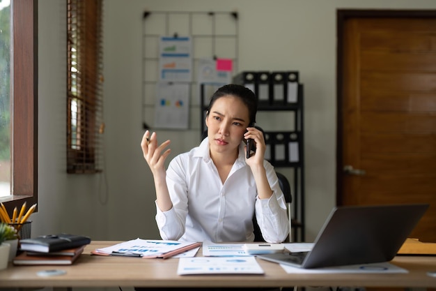 Téléphone en colère et femme asiatique stressée lors d'un appel professionnel au sujet de l'audit fiscal et du courrier électronique de conformité sur un ordinateur portable au bureau