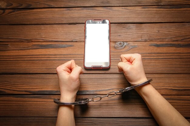 Un téléphone avec la dépendance des mains sur un fond en bois