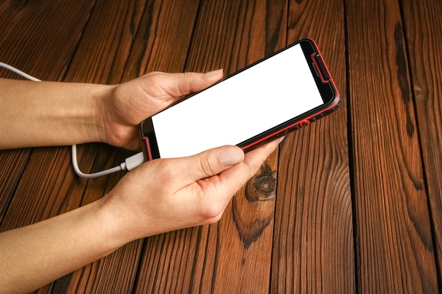 Un téléphone avec la dépendance des mains sur une surface en bois