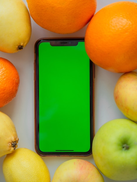 Un téléphone avec un écran vert se trouve parmi les fruits photo de haute qualité