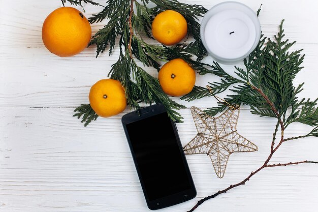 Téléphone élégant avec écran vide et oranges de Noël et étoile d'or sur fond en bois rustique blanc mise à plat salutation saisonnière et texte de l'espace de concept de publicité shopping