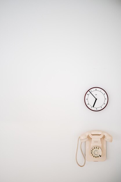 Photo téléphone et horloge sur le mur blanc
