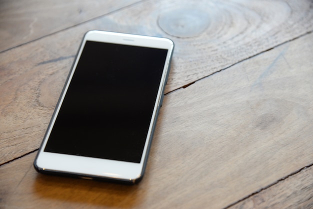 Téléphone intelligent blanc dans un étui noir sur la table en bois préparé pour les équipes de direction à contacter le client en affaires