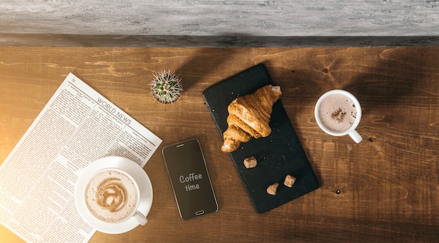 Téléphone intelligent et grains de café frits noirs au café avec cookie et gâteau sur fond texturé foncé