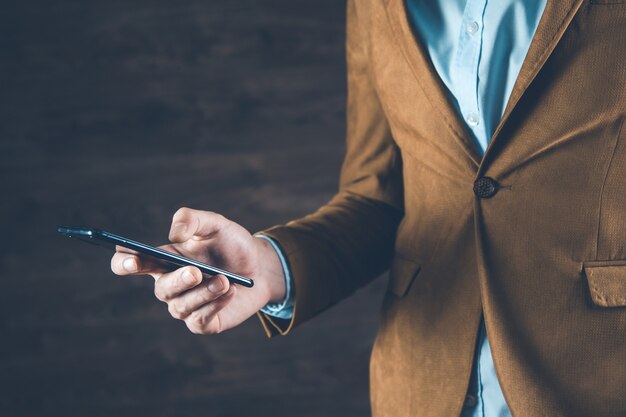 Téléphone intelligent de main de l'homme sur le fond sombre