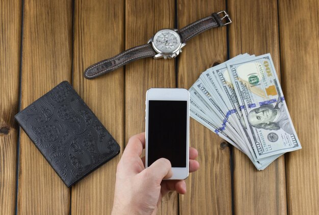 Téléphone en main et passeport avec montre sur table en bois