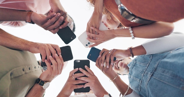 Photo téléphone mains et communication avec des amis debout dans un caucus ou un cercle d'en bas pour le réseautage médias sociaux mobiles et 5g avec un groupe d'amis homme et femme connectés à internet ensemble