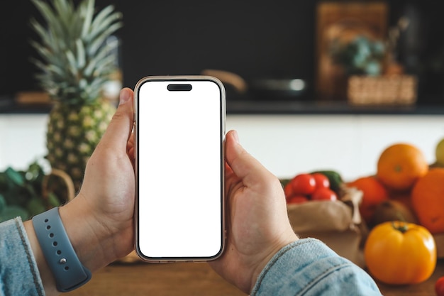 Téléphone en mains avec un écran isolé sur le fond de la cuisine le concept de comptage des calories et une bonne nutrition