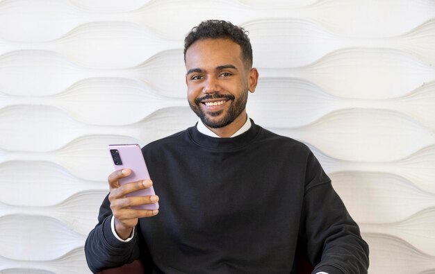 Téléphone mains et médias sociaux avec un homme noir tapant un message texte assis sur un canapé dans sa maison Communication mobile et mise en réseau avec un homme discutant depuis le salon