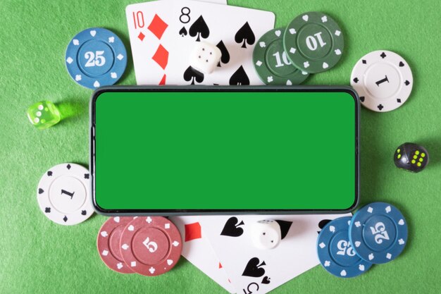 Téléphone maquette avec clé chroma et cartes à jouer et jetons de poker dans le casino