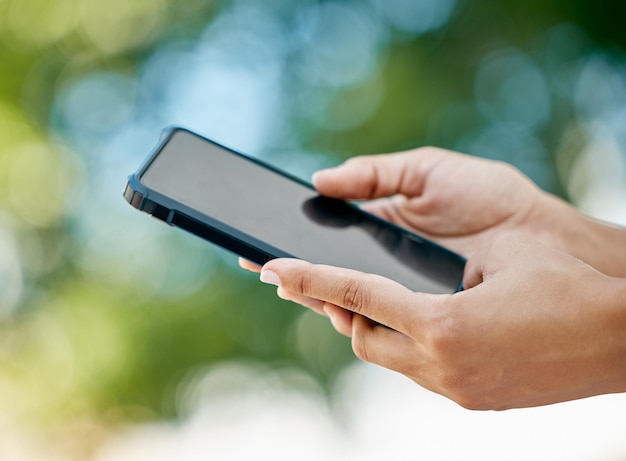 Téléphone maquette et gros plan des mains dans la nature avec écran blanc vide et noir Communication technologique et personne tenant un smartphone dans un parc extérieur pour les médias sociaux Internet et l'application mobile