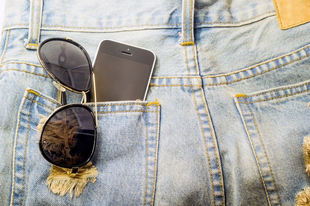 téléphone moblie et lunettes dans la poche de jeans